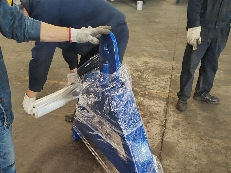 Workers wrapping components of concrete mixture pump in factory